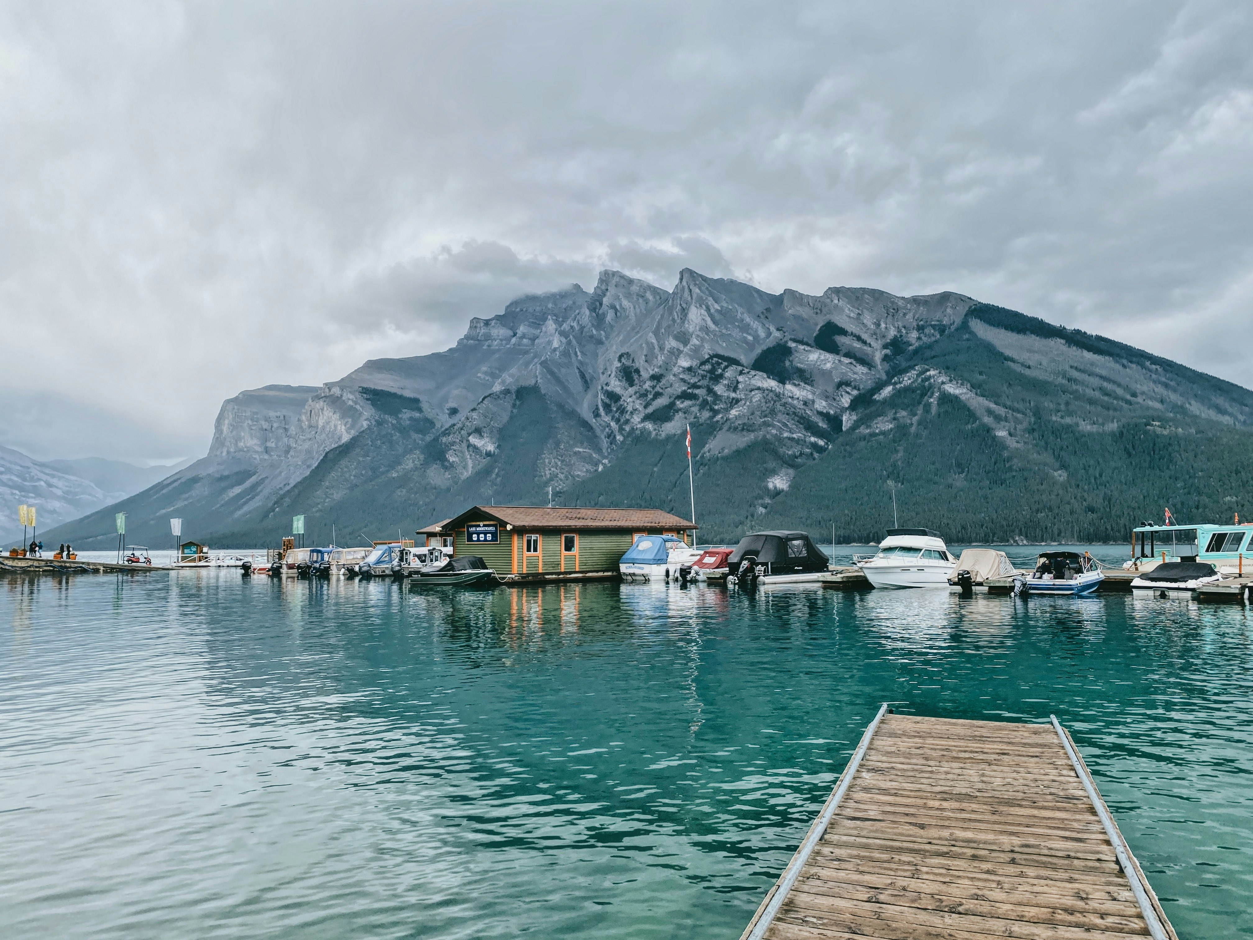 brown wooden dock on lake near mountain under white cloudy sky during daytime